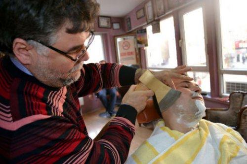 Balta ve ateşle saç sakal traşı yapıyor