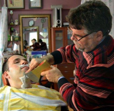 Balta ve ateşle saç sakal traşı yapıyor