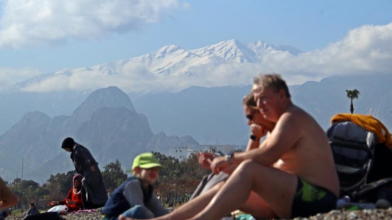 Antalya’da zirve beyaza bürünürken sahilde denize girdiler