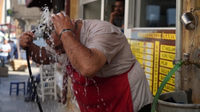 Bayburt'ta lokanta esnafı serinlemek için bütün vücudunu hortumla yıkıyor