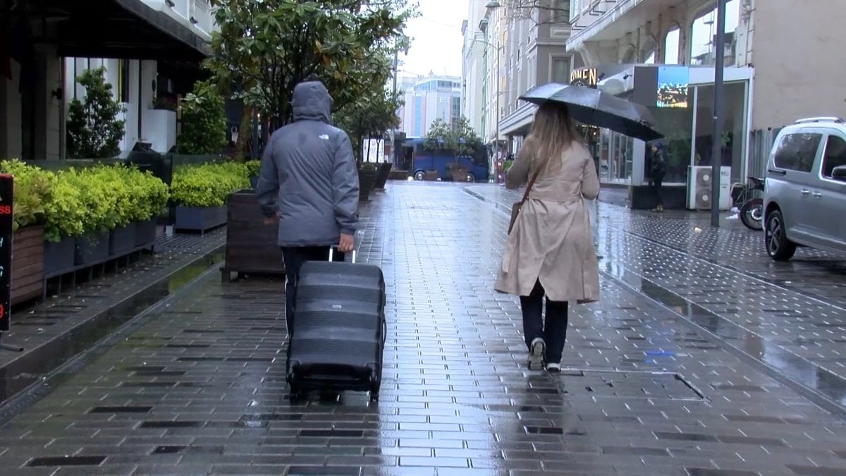 Taksim'de kapatılan yollar nedeniyle turisteler valizlerle yağmur altında yürüdü