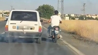 Şanlıurfa'da motosiklet sürücüsü, otomobile tutunarak yol aldı