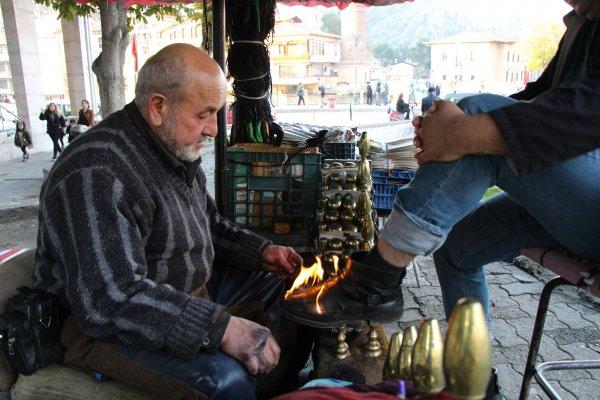 Amasyalı adam ayakkabıları ateşle boyuyor