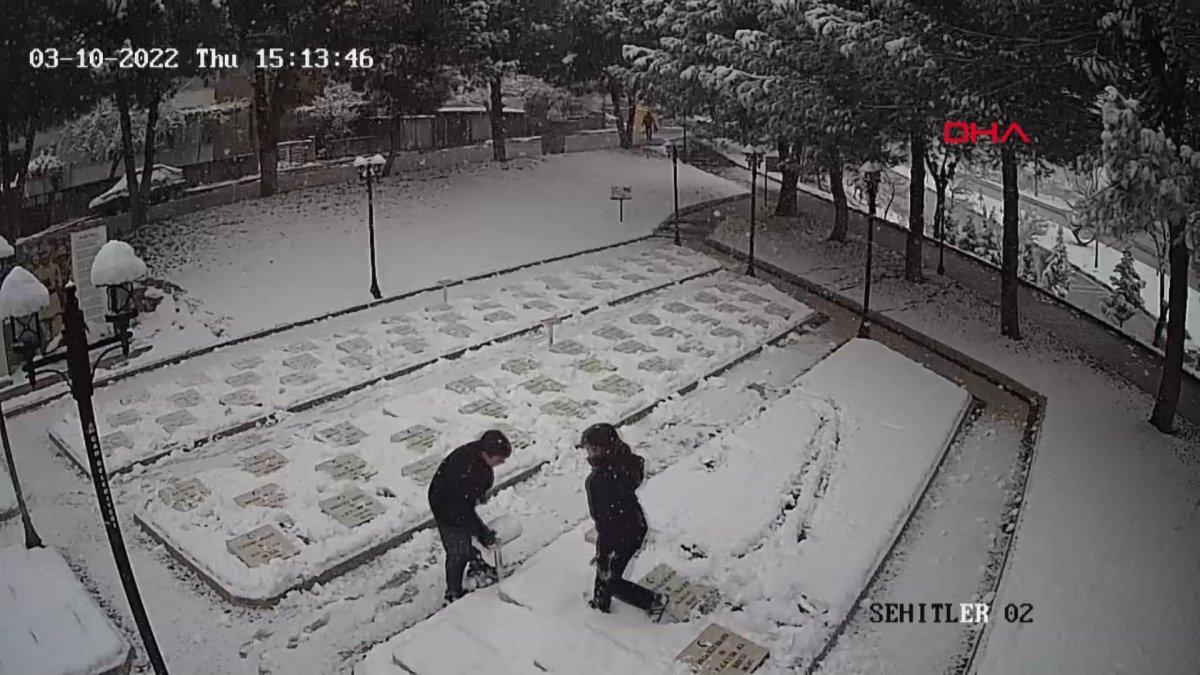 Çanakkale'de 2 genç, beyaza bürünen şehitlikteki mezar taşlarını temizledi